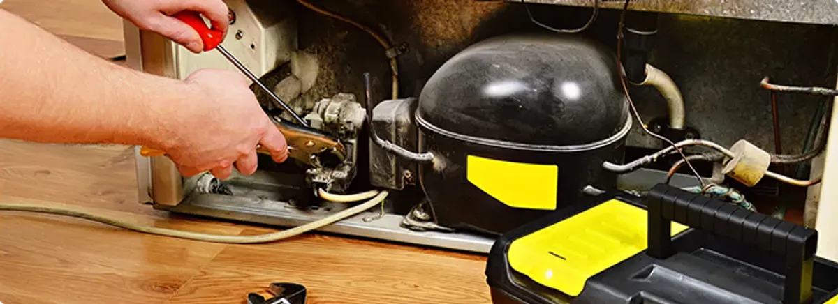 Refrigerator repair technician fixing the compressor and wiring in Fort Shafter, HI