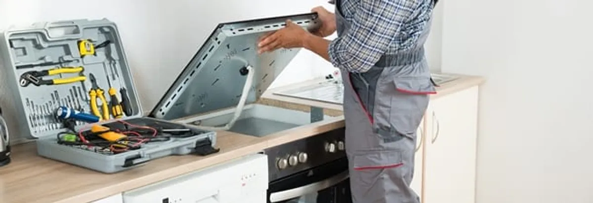 Cooktop repair technician lifting a built-in stovetop for service in Honolulu, HI