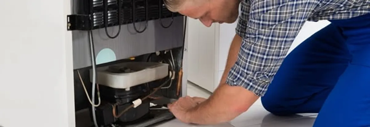 Refrigerator repair technician servicing the compressor and condenser area in Honolulu, HI